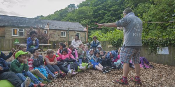 Tutor talking to group of children at YHA Boggle Hole
