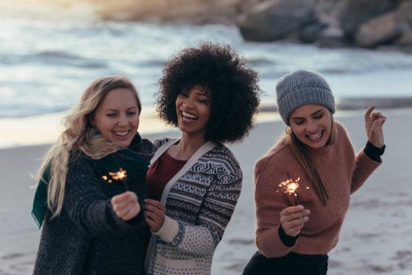 Group of women holding sparklers on a beach