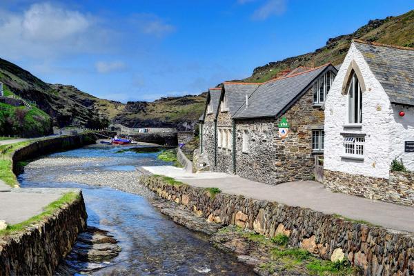 Stone hostel building by a river estuary with a blue sky in the background