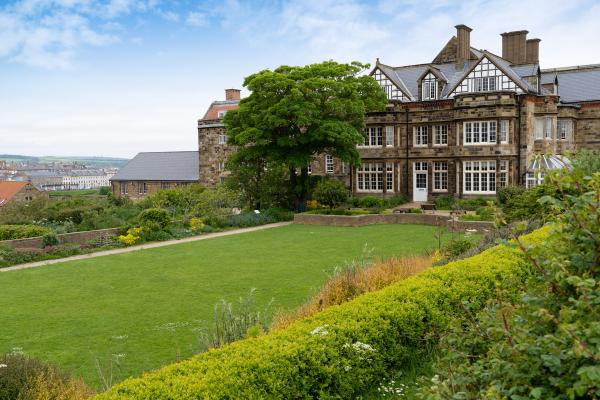 Large mansion building and grounds with stone walls and white wooden window frames