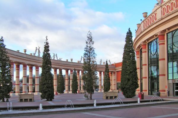 Large shopping centre exterior with stone columns and surrounding trees