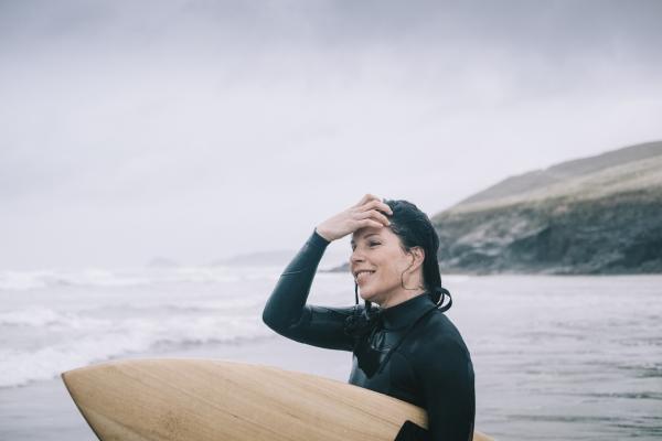 Watersports at Lizard Point, woman with surfboard looking out to sea