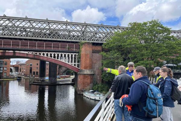 Group of walks standing next to bridge over a canal