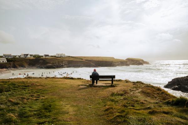 Person sat on a bench watching the sea at Treyarnon Bay
