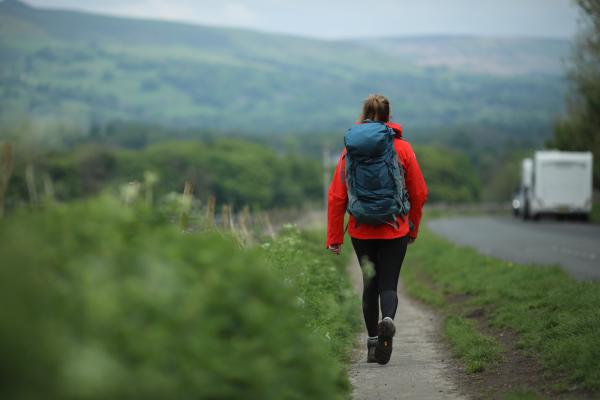 Woman hiking down a path with a rucksack and coat