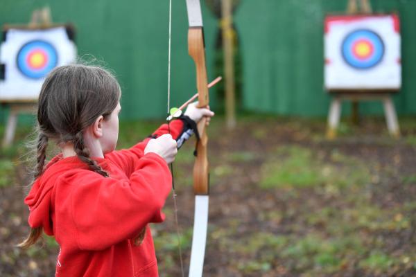 Young person taking part in archery on a school trip