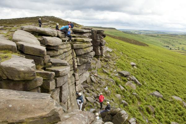 Group climbing a rock in Edale