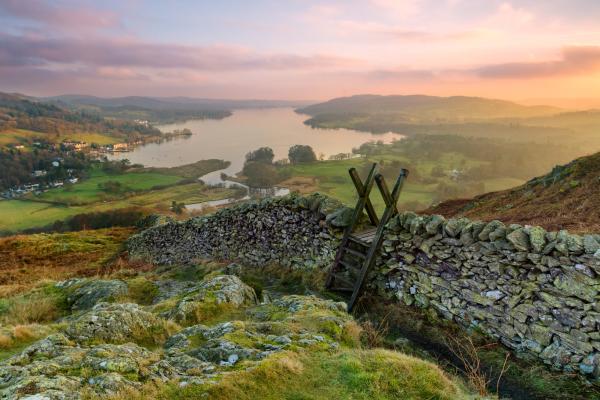 Beautiful sunset over Windermere in the Lake District with a stile and stone wall in the foreground