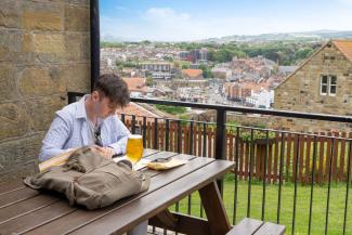 person sat on bench having a drink man sat on a bench with pint of beer overlooking Whitby