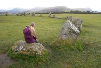 Child sitting on a large boulder in a stone circle