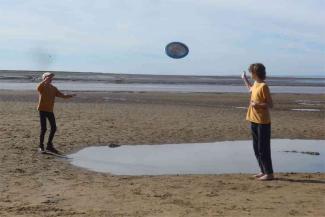 Two children throwing a frisbee on a beach