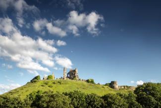 Castle ruins on top of a hill with blue skies above