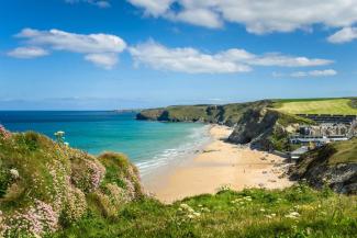 Green cliffs overlooking a beach and blue sea in the sunshine