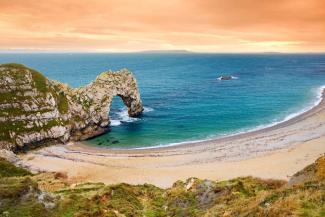 Durdle Door of the coast of Cornwall Sandy beach and arch-shaped rock formation overlooking the blue ocean