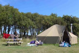 Family lounging outside a canvas bell tent