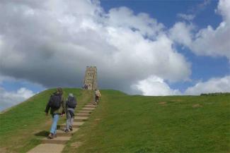 Family walking up a hill towards a stone marker
