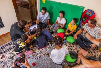 Group of adults and children gathered around a laptop