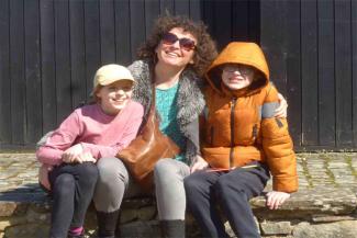 Mum and two childing smiling while sitting on a wall