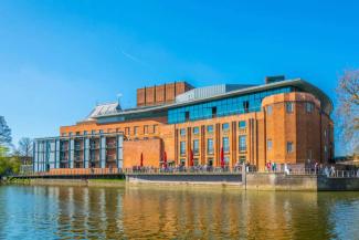 Royal Shakespeare Company theatre in Stratford-upon-Avon Large brick theatre building by a river