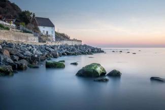 White stone cottage next to a bay with views out to sea