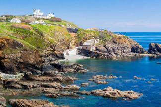 Tintagel cliff-edge overlooking the sea Buildings on top of a grassy cliff overlooking a blue ocean