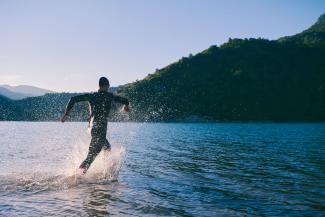 Swimmer wearing a wetsuit wading into a lake