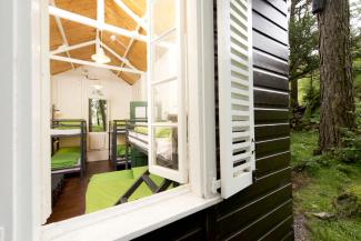 Window into an Anglesey hut at YHA Idwal Cottage Wooden hut with window open showing a bright space with bunk beds
