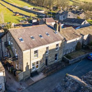 Stone hostel building with houses and green rolling hills in the background