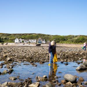 People on the beach with YHA Port Eynon in the background