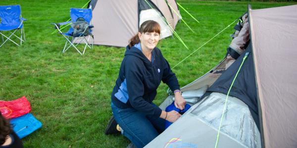 Woman kneeling by a tent outdoors
