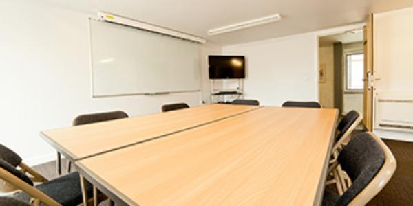 Meeting room at YHA Berwick with white walls and a wooden table and chairs