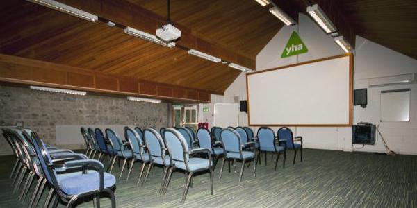 Meeting room at YHA Castleton Losehill Hall with rows of chairs facing a projector screen