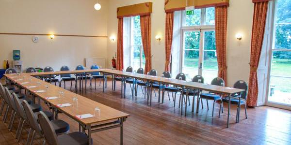 Meeting room at YHA Chester Trafford Hall with large windows, u-shaped table configuration and chairs