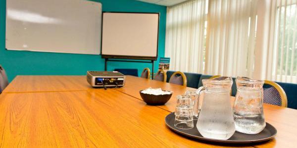 Meeting room at YHA Conwy with blue painted walls, a flipchart, wooden table and chairs
