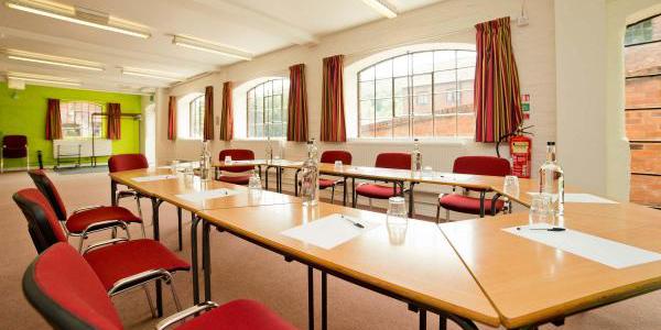 Meeting room at YHA Ironbridge Coalport with large windows, u-shaped table configuration and red chairs
