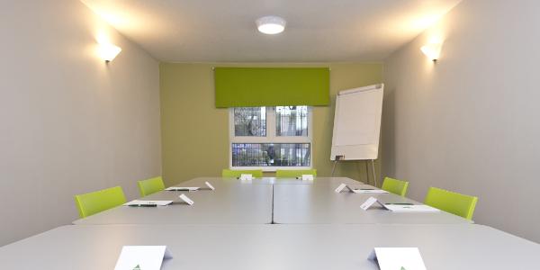 Meeting room at YHA Liverpool Albert Dock with white walls, a white table and green chairs