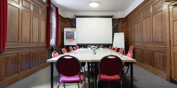 Meeting room at YHA London St Paul's with wooden wainscoating on the walls plus a table and chairs in the centre