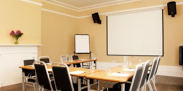 Meeting room at YHA Stratford-upon-Avon with projector screen, flip chart, table and chairs