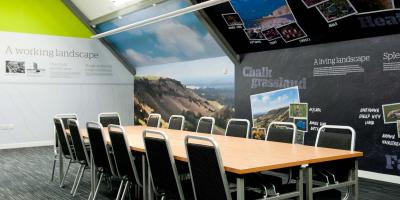 Room with illustrations on the walls, a large wooden table and chairs