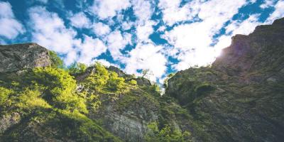 Rocky cliff face beneath a blue sky with clouds