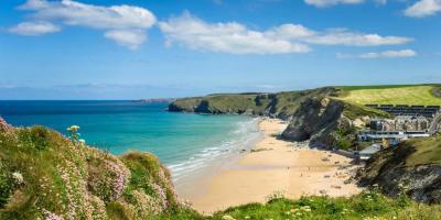 Green cliffs overlooking a beach and blue sea in the sunshine