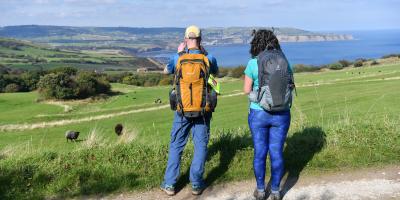 Walkers looking over a field out towards the sea