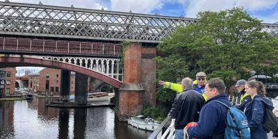 Group of walks standing next to bridge over a canal