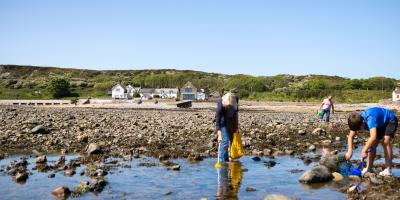 People on the beach with YHA Port Eynon in the background