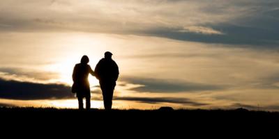 Two people walking on a beach at sunset