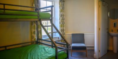 Bedroom with a single bunk bed over a double bed and an open door into an en-suite bathroom
