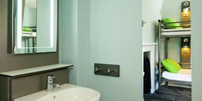 Bathroom with an open door leading to a bedroom with bunk beds