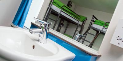 Sink and mirror with two sets of bunk beds in the reflection
