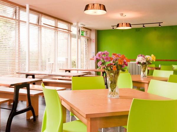 Dining room with green walls, large windows and wooden tables with bench seating and chairs