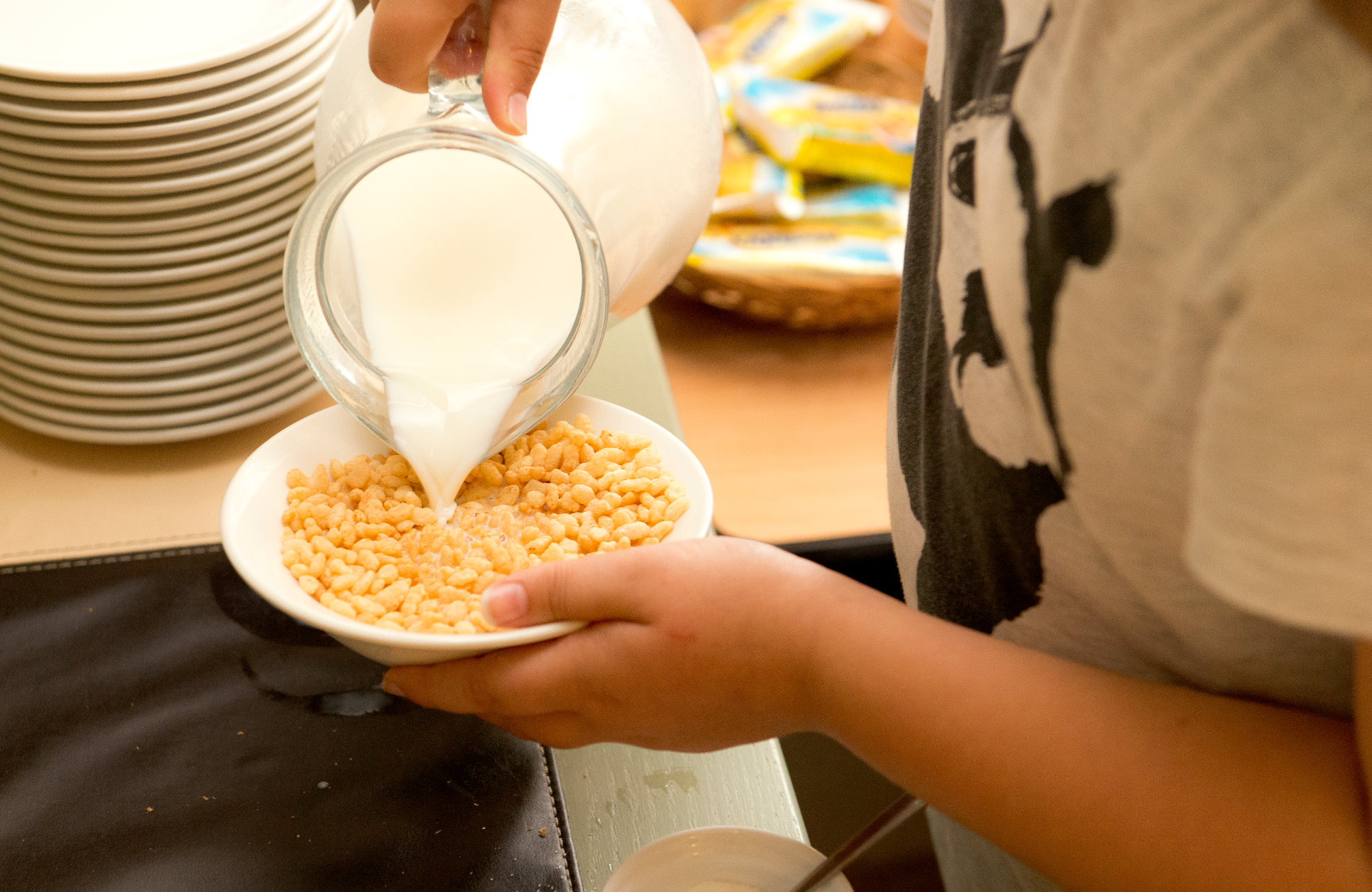 Child pouring milk into cereal